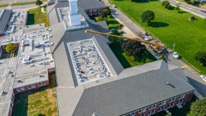 Side angle of RENU team positioning HVAC units during school rooftop installation